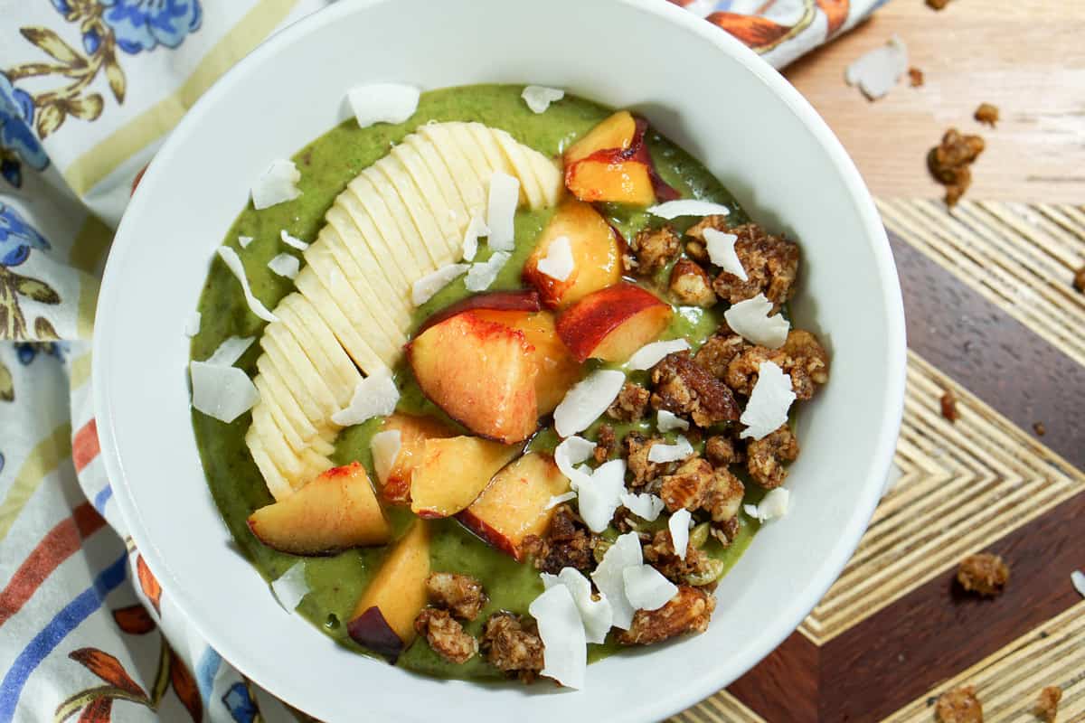 Peaches n Kale Smoothie Bowl Recipe - A delicious peaches n' cream smoothie bursting with antioxidants and protein. Topped with fruit and wholesome granola, it's a perfect way to start the day or treat yourself at night. 