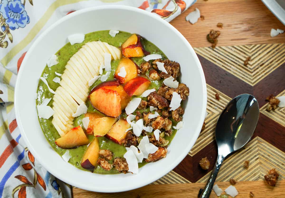 Peaches n Kale Smoothie Bowl Recipe - A delicious peaches n' cream smoothie bursting with antioxidants and protein. Topped with fruit and wholesome granola, it's a perfect way to start the day or treat yourself at night.