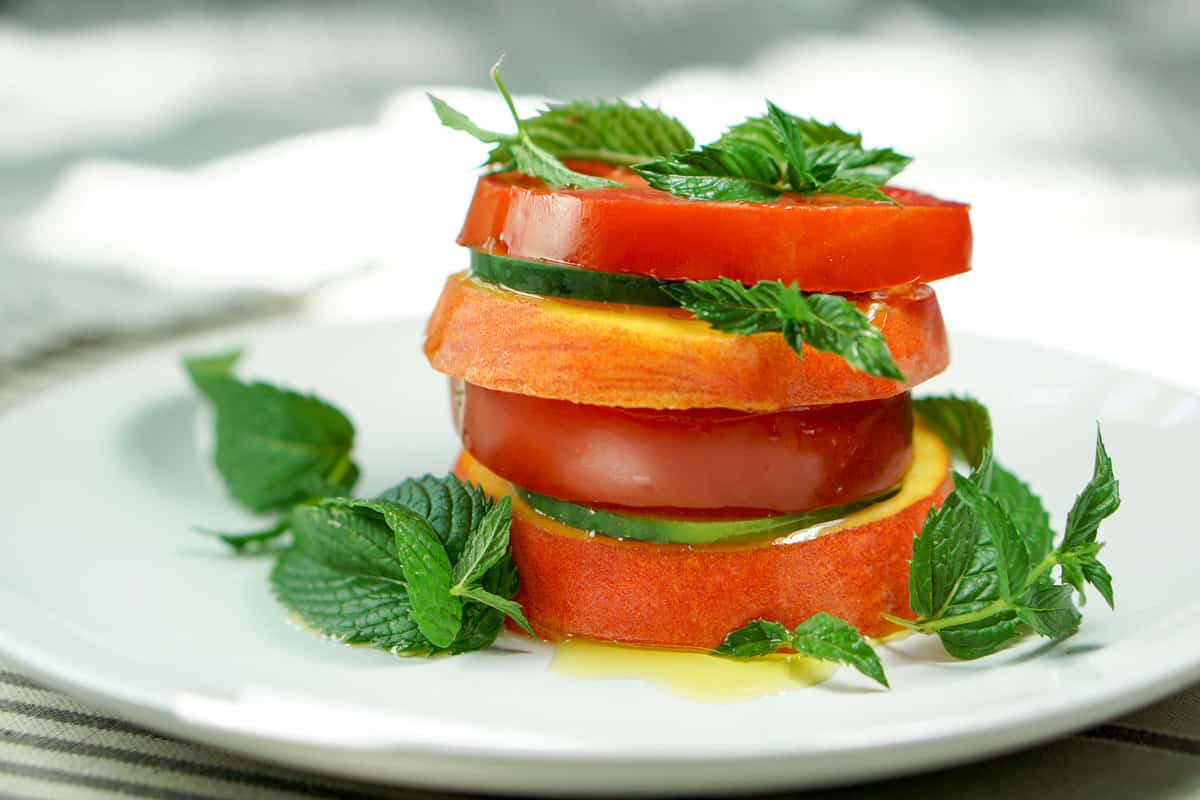 Peach Tomato Mint Salad Stack Recipe - Simply slice fresh peaches, tomatoes and cucumbers, stacking with mint to create this great appetizer, light meal or side salad. This will definitely be a recipe to impress your friends at your next barbq or family dinner!