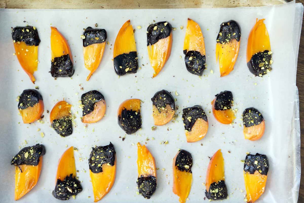 The flavors of buttery cinnamon persimmons, bittersweet chocolate, and freshly crushed pistachios make this quick, tasty and impressive dessert. Chocolate covered persimmons use just 5 ingredients, are ready in just a few minutes, and are sure to impress both your sweet-tooth and health-kick friends.