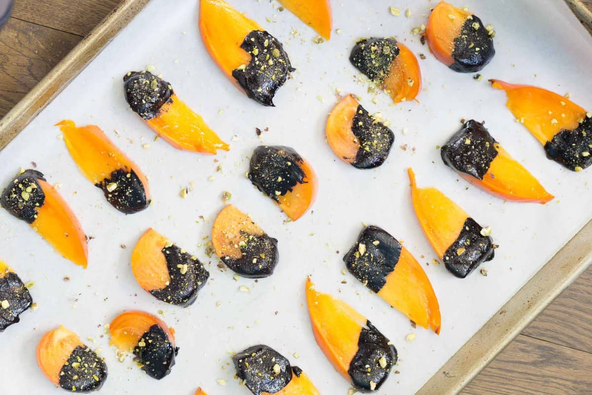 The flavors of buttery cinnamon persimmons, bittersweet chocolate, and freshly crushed pistachios make this quick, tasty and impressive dessert. Chocolate covered persimmons use just 5 ingredients, are ready in just a few minutes, and are sure to impress both your sweet-tooth and health-kick friends.