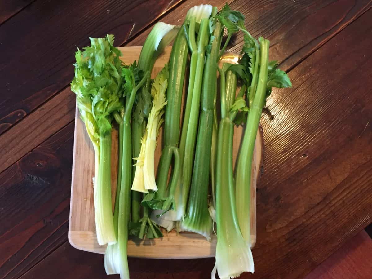 tallos de apio en una tabla de corte esperando a ser convertidos en jugo. Lleno de sales minerales buenas para curar el intestino