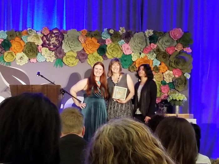 Three women holding an award for helping shift the community to safer products at ShiftCon Media