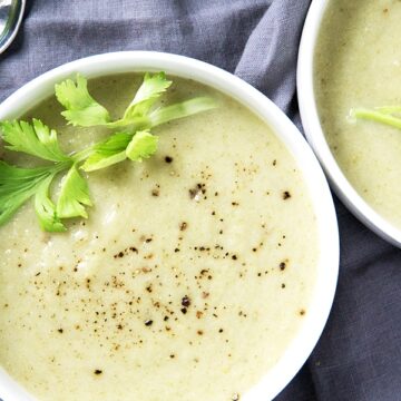 green cream of celery soup on blue grey napkin with spoon to the side