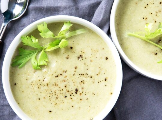 green cream of celery soup on blue grey napkin with spoon to the side