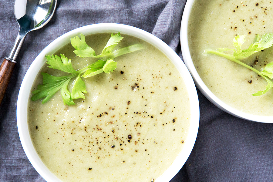 green cream of celery soup on blue grey napkin with spoon to the side