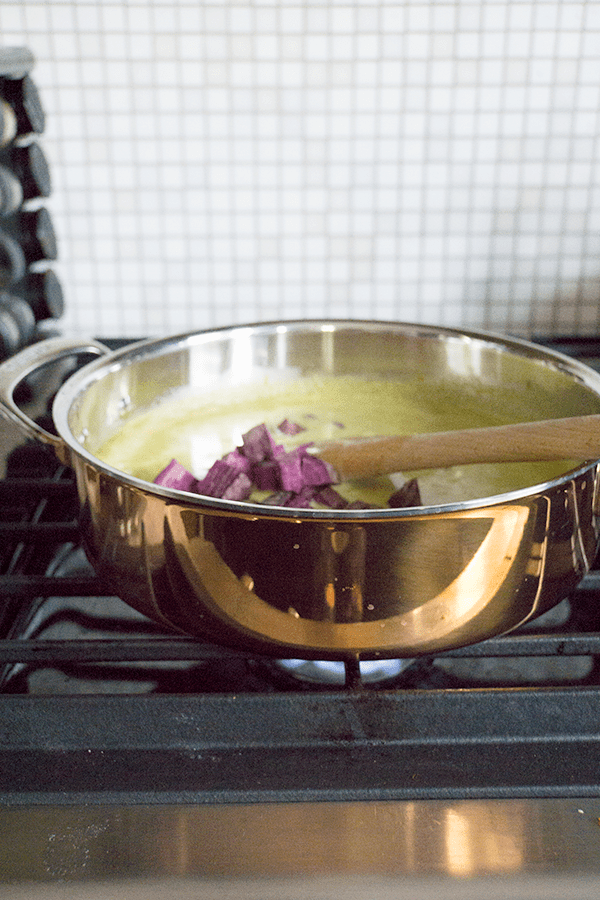 Adding purple potatoes to the copper pot of halibut curry
