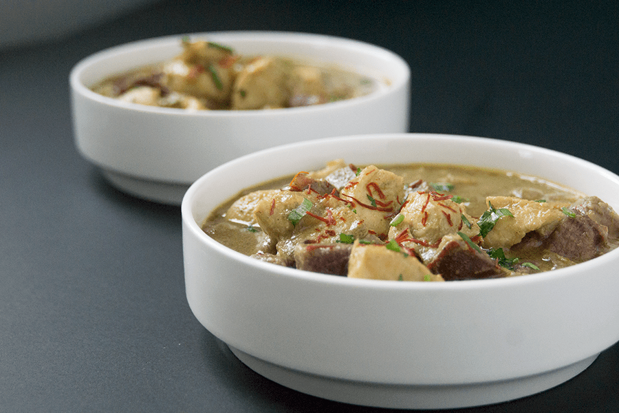 Purple potato halibut curry with cardamom basmati in white bowls on a black background