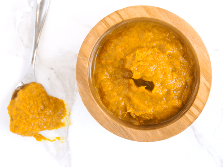 orange Ginger Turmeric Honey Chili Sauce with Dried Red Chilies is spicy, tangy and fresh, making a great marinade, dip, and homemade hot sauce. It's also chocked full of superfoods. in wooden bowl next to spoon dripping sauce on white marble