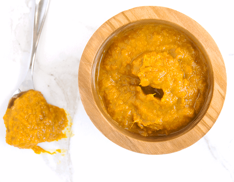 orange Ginger Turmeric Honey Chili Sauce with Dried Red Chilies is spicy, tangy and fresh, making a great marinade, dip, and homemade hot sauce. It's also chocked full of superfoods. in wooden bowl next to spoon dripping sauce on white marble