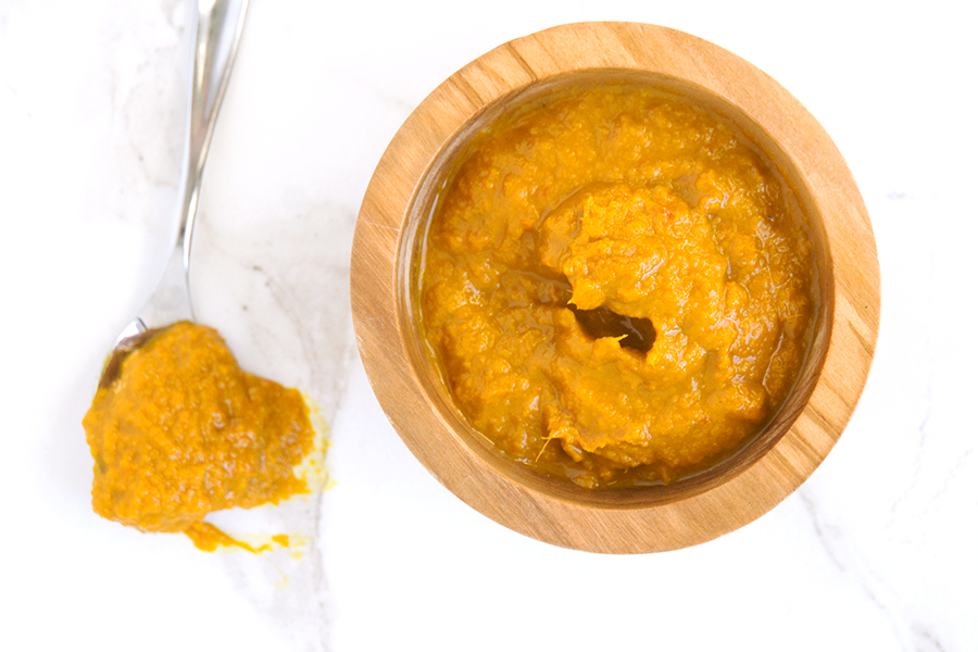 orange Ginger Turmeric Honey Chili Sauce with Dried Red Chilies is spicy, tangy and fresh, making a great marinade, dip, and homemade hot sauce. It's also chocked full of superfoods. in wooden bowl next to spoon dripping sauce on white marble