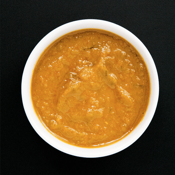 Ginger Turmeric Honey Chili Sauce with Dried Red Chilies in a white bowl on black background. 
