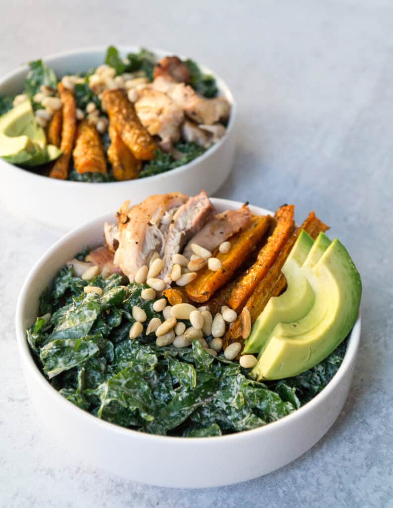 Kale tossed in creamy tahini cashew Caesar dressing topped with avocado, pine nutes, roasted carrot spears and grilled chicken thighs