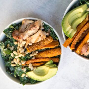 Superfood Kale Caesar salad with avo, chicken thighs, pine nuts, and creamy tahini cashew Caesar dressing