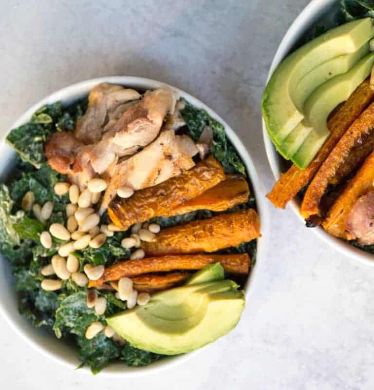 Superfood Kale Caesar salad with avo, chicken thighs, pine nuts, and creamy tahini cashew Caesar dressing