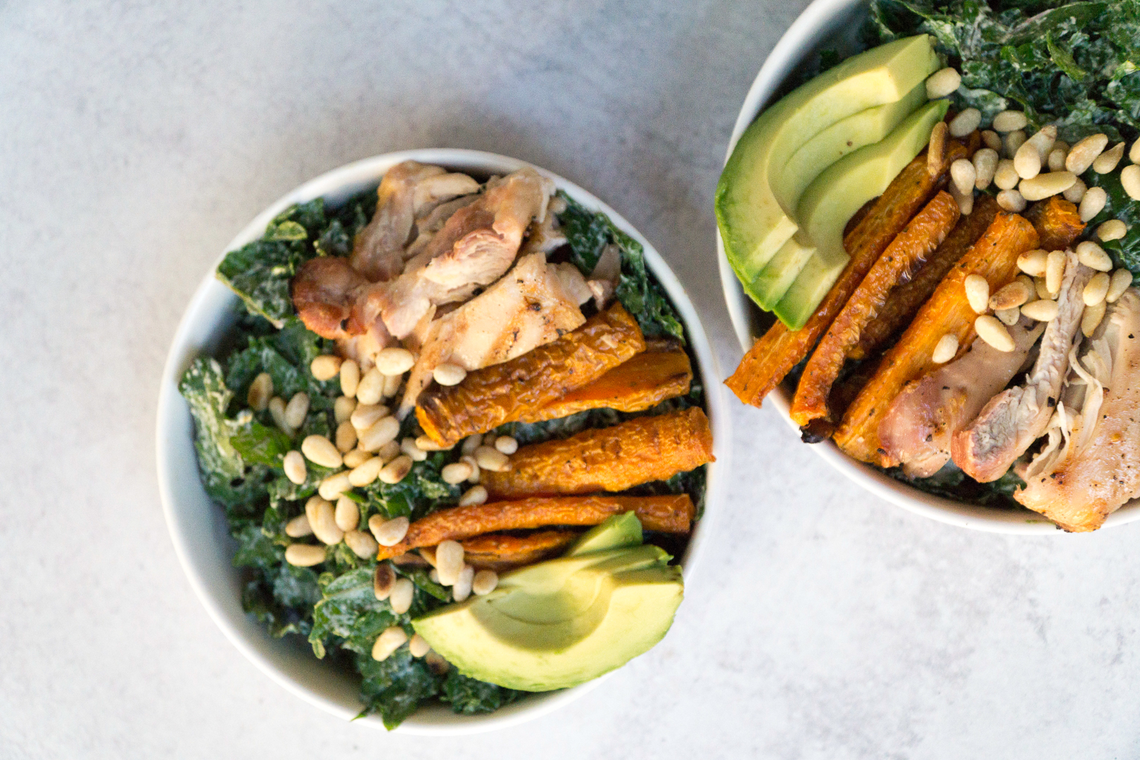 Superfood Kale Caesar salad with avo, chicken thighs, pine nuts, and creamy tahini cashew Caesar dressing