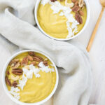 Orange Pumpkin smoothie bowls topped with roasted nuts and coconut flakes, with linen napkins
