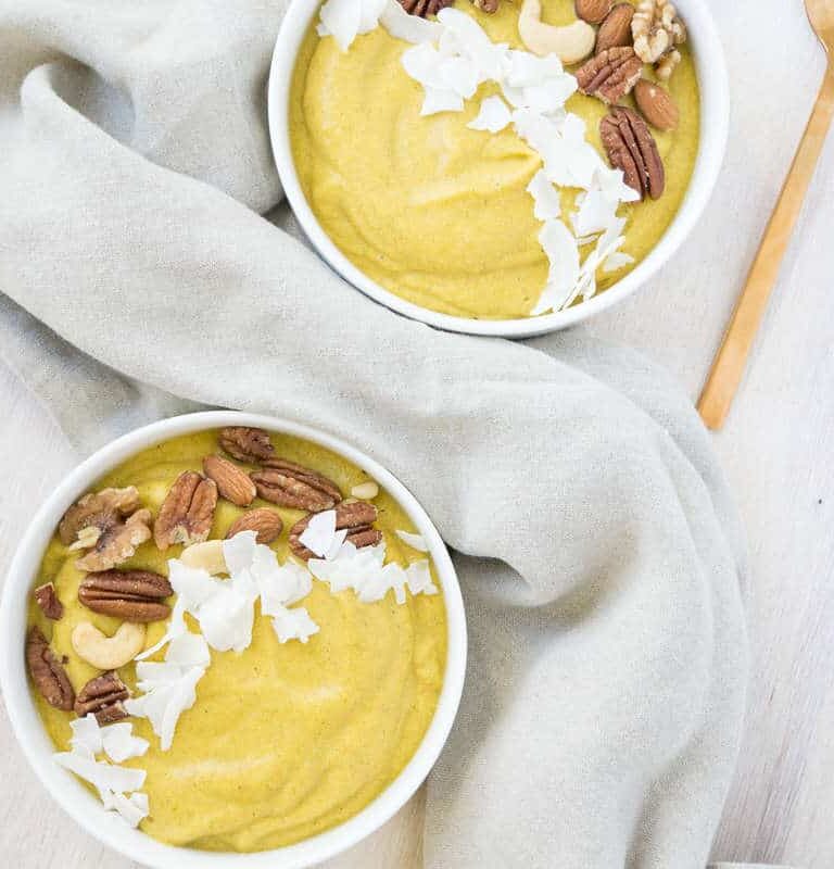 Orange Pumpkin smoothie bowls topped with roasted nuts and coconut flakes, with linen napkins