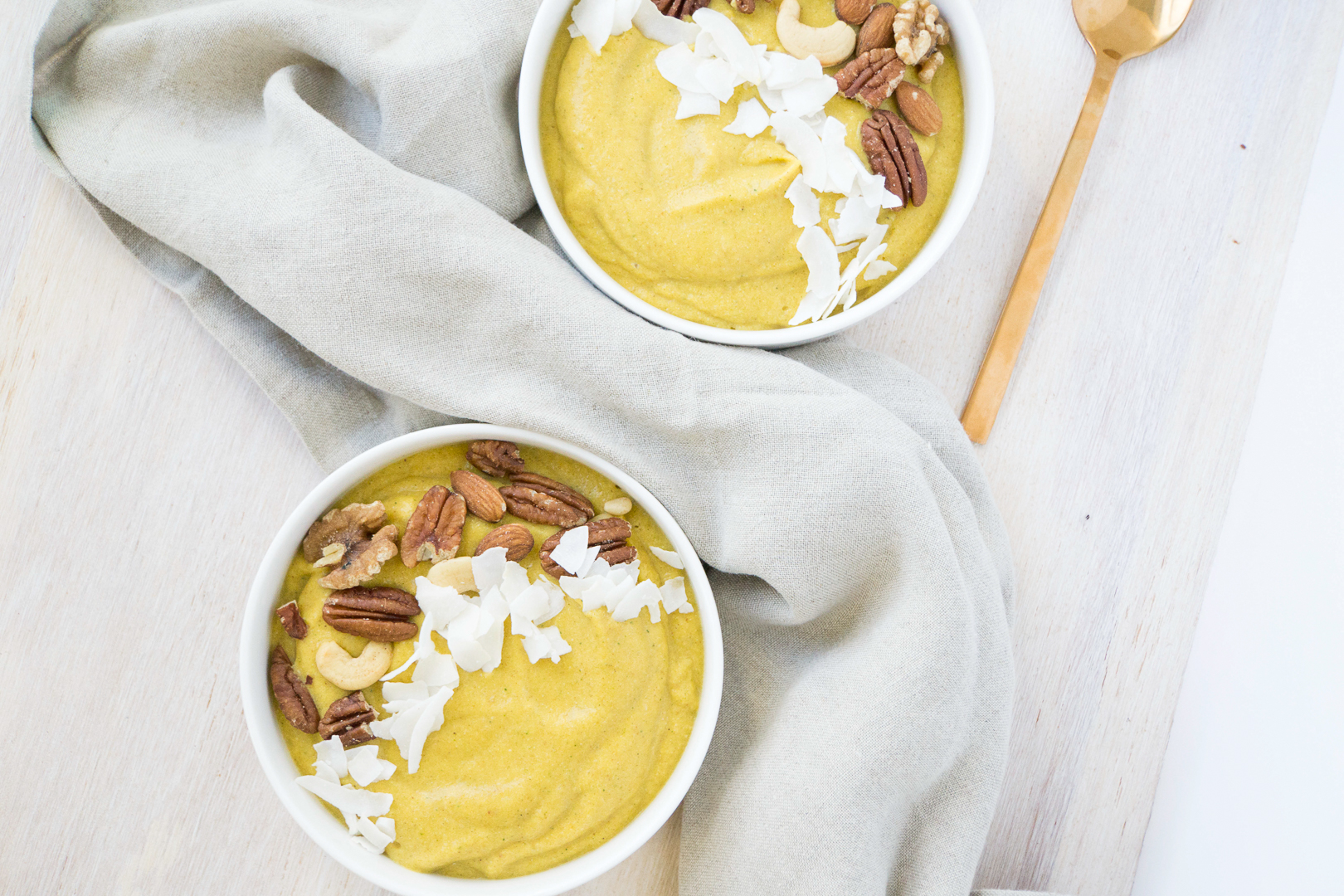 Orange Pumpkin smoothie bowls topped with roasted nuts and coconut flakes, with linen napkins