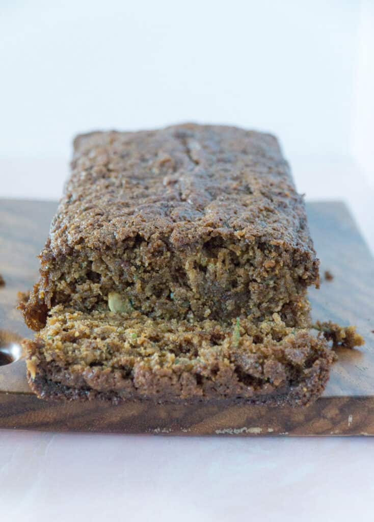 Zucchini bread loaf with one slice cut. Gluten free on cutting board