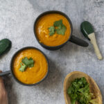 Grabbing a mug of Pumpkin Thai Curry Soup garnished with cilantro