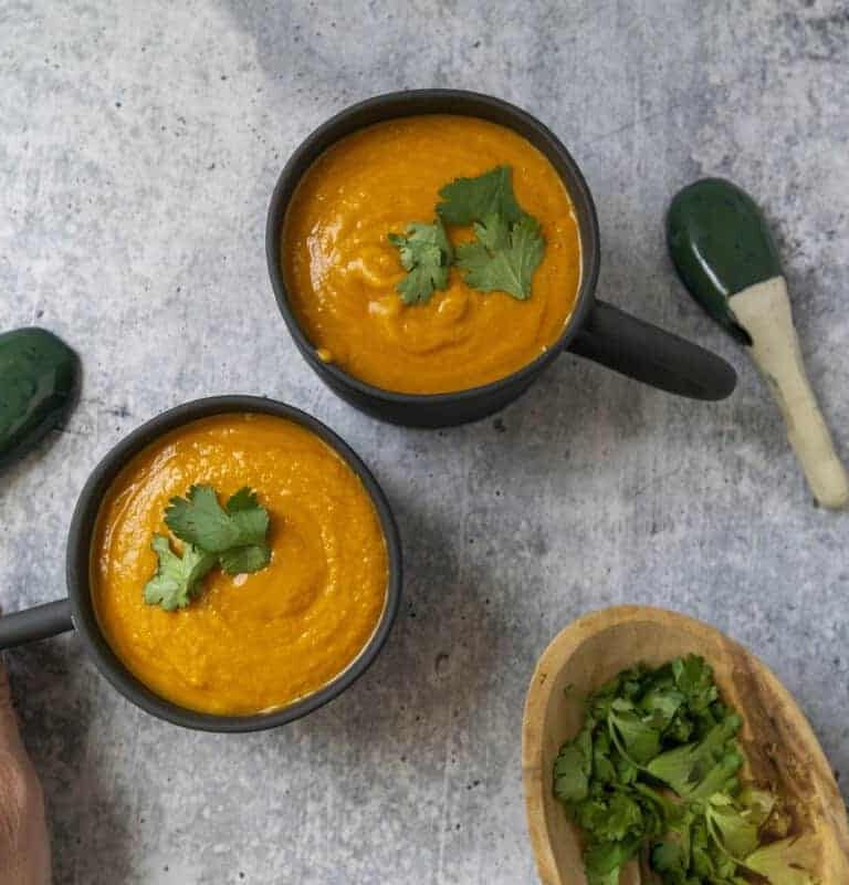 Grabbing a mug of Pumpkin Thai Curry Soup garnished with cilantro
