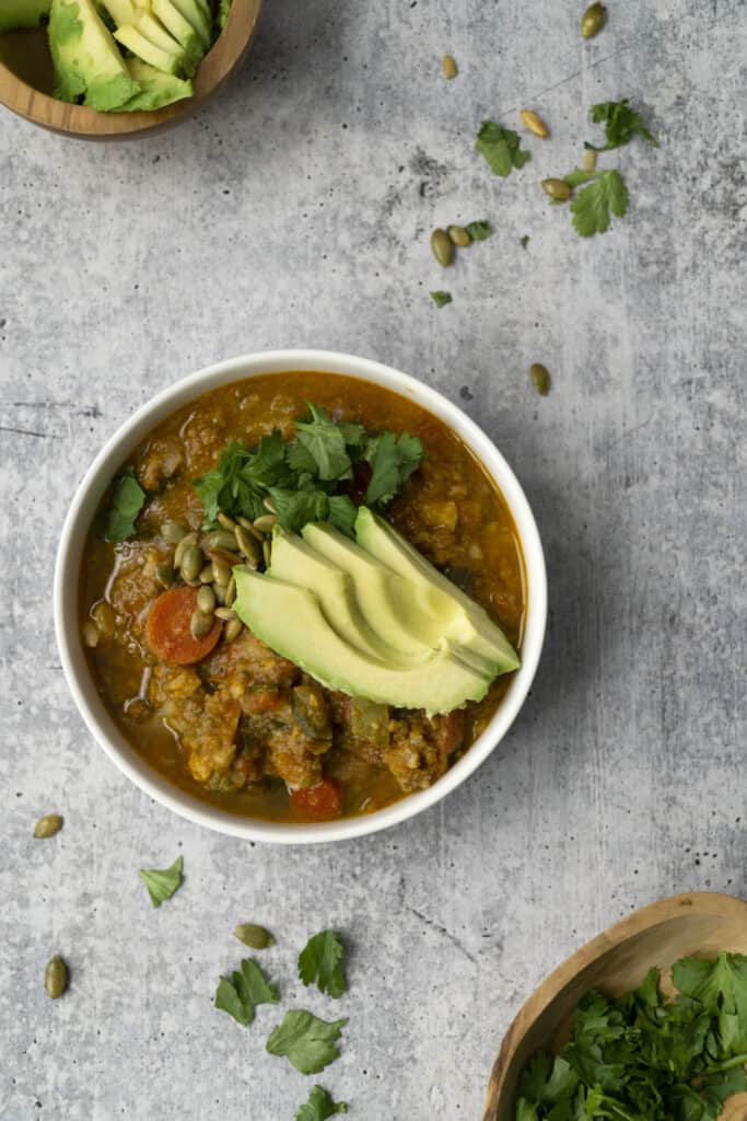 overhead bowl of pumpkin chili with cilantro and avocado