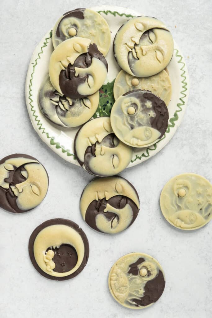 White and Dark Chocolate Sun and Moon Molds falling off of a plate