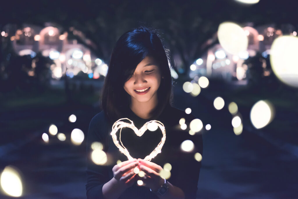 girl holding light-up heart in dark street