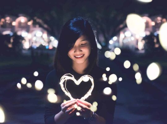 girl holding light-up heart in dark street