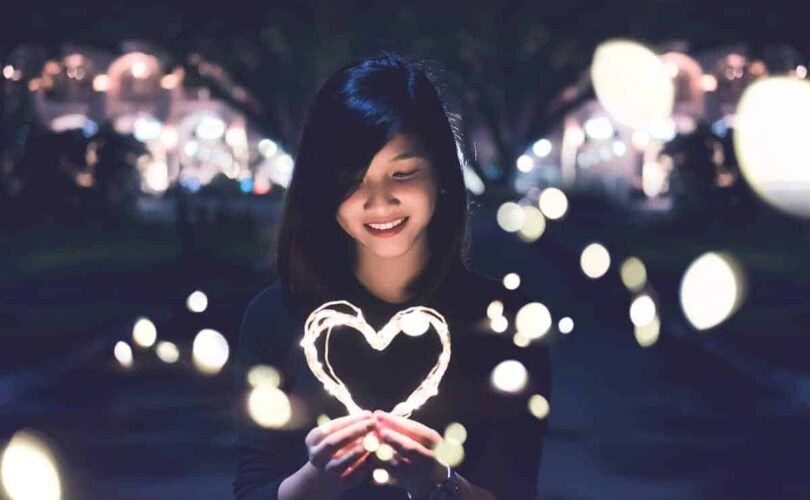 girl holding light-up heart in dark street
