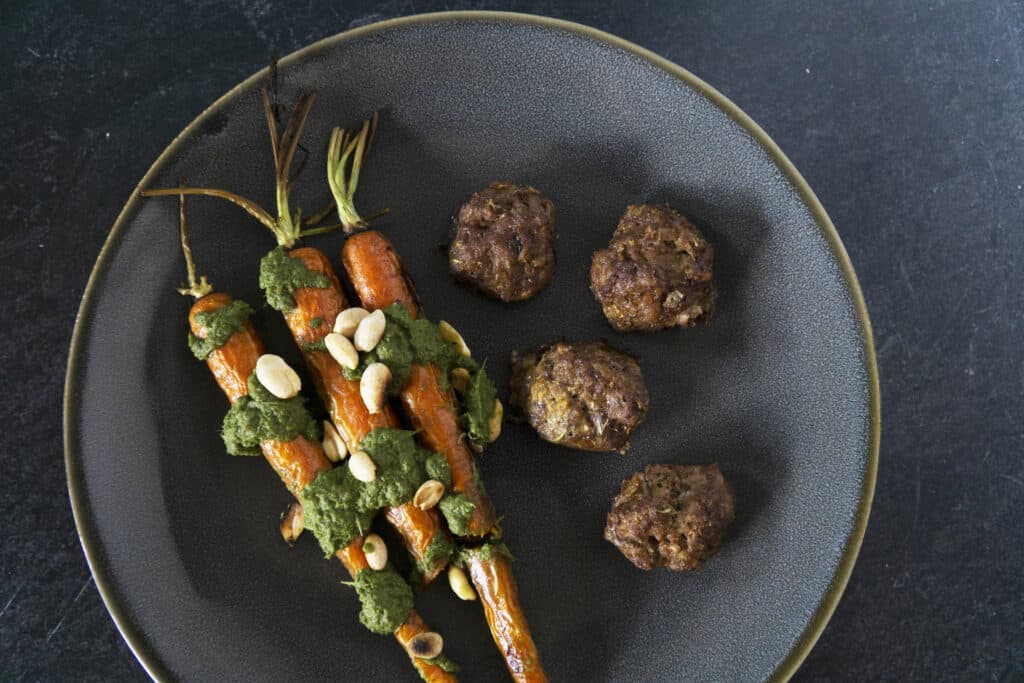 Meatballs on gray plate with carrots and carrot top pesto
