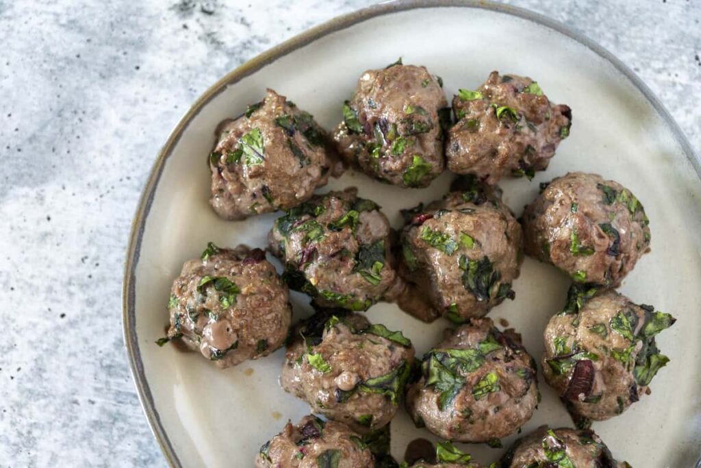 Beet Green Meatballs on white plate - close up