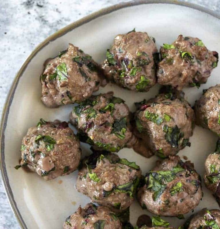 Beet Green Meatballs on white plate - close up