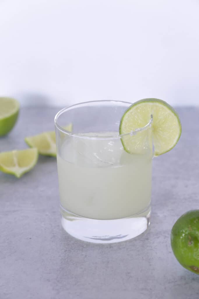 side view of Lime wedge in salted margarita glass with limes