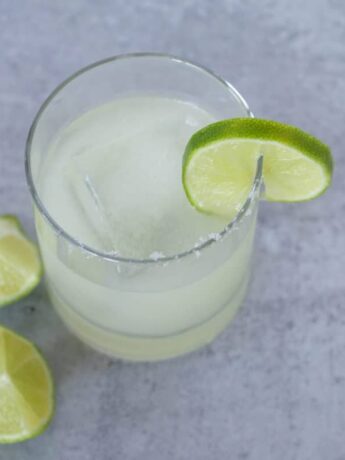 Salt rimmed margarita in glass with limes