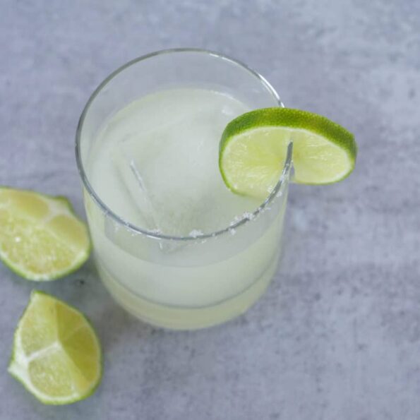 Salt rimmed margarita in glass with limes
