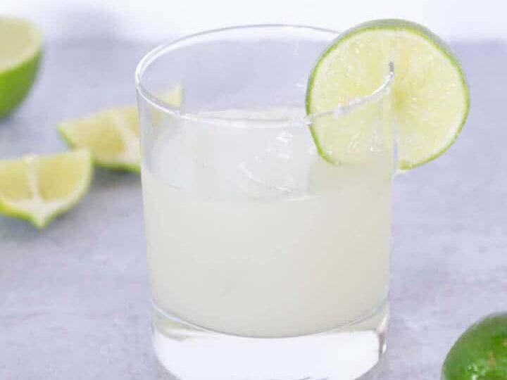 side view of Lime wedge in salted margarita glass with limes