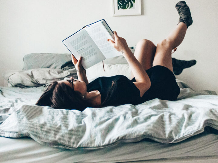 joyous woman on bed reading with socked feet in the air
