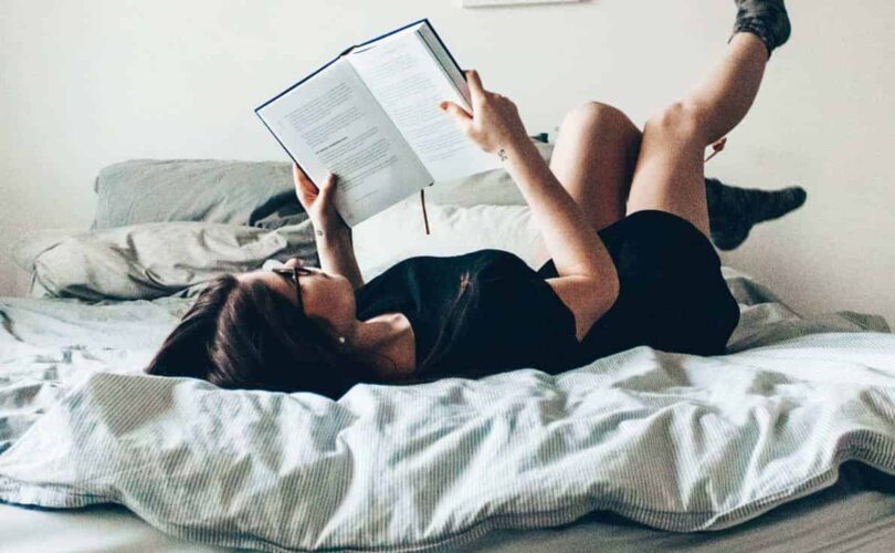 joyous woman on bed reading with socked feet in the air