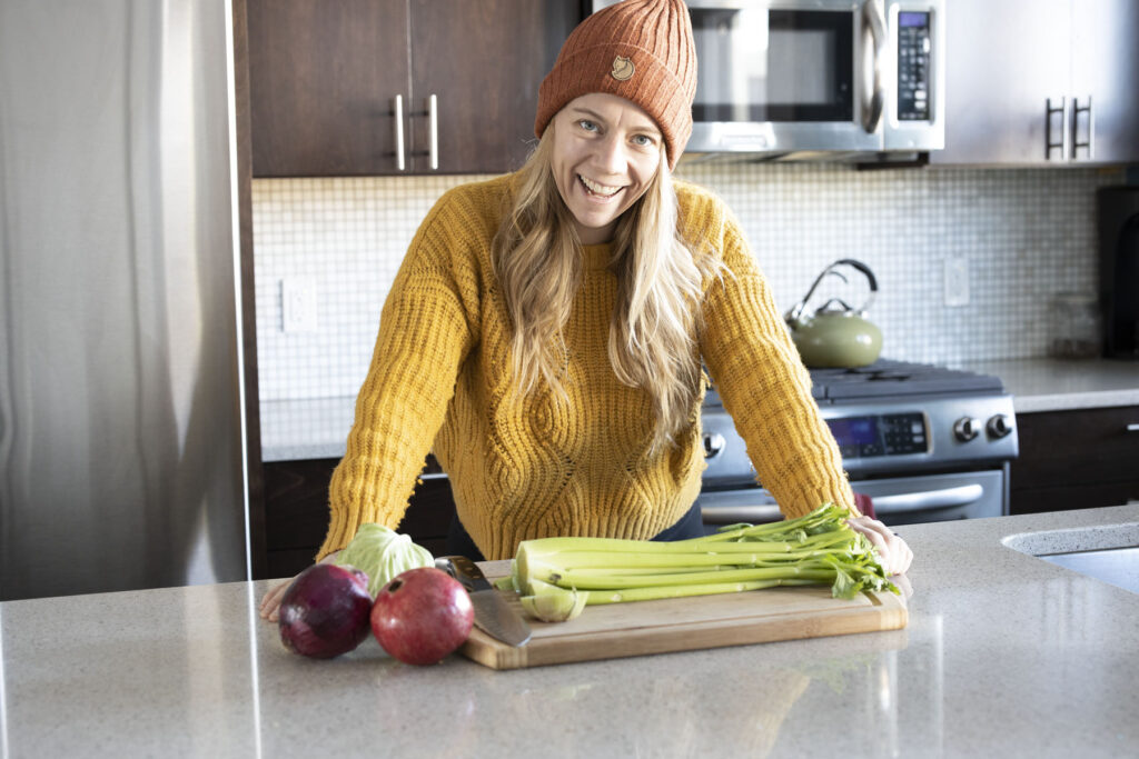 Girl in sweater in kitchen cutting celery