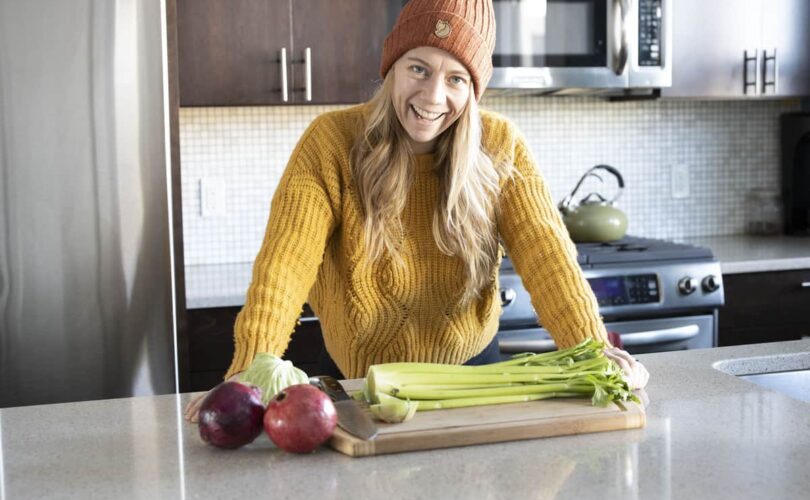 Girl in sweater in kitchen cutting celery