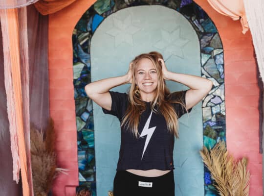 Girl with hands on hair and lightening bowie shirt - feeling energized in front of colorful background