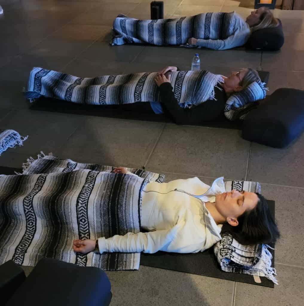 women doing meditation practice, laying on yoga mats with mexican blankets