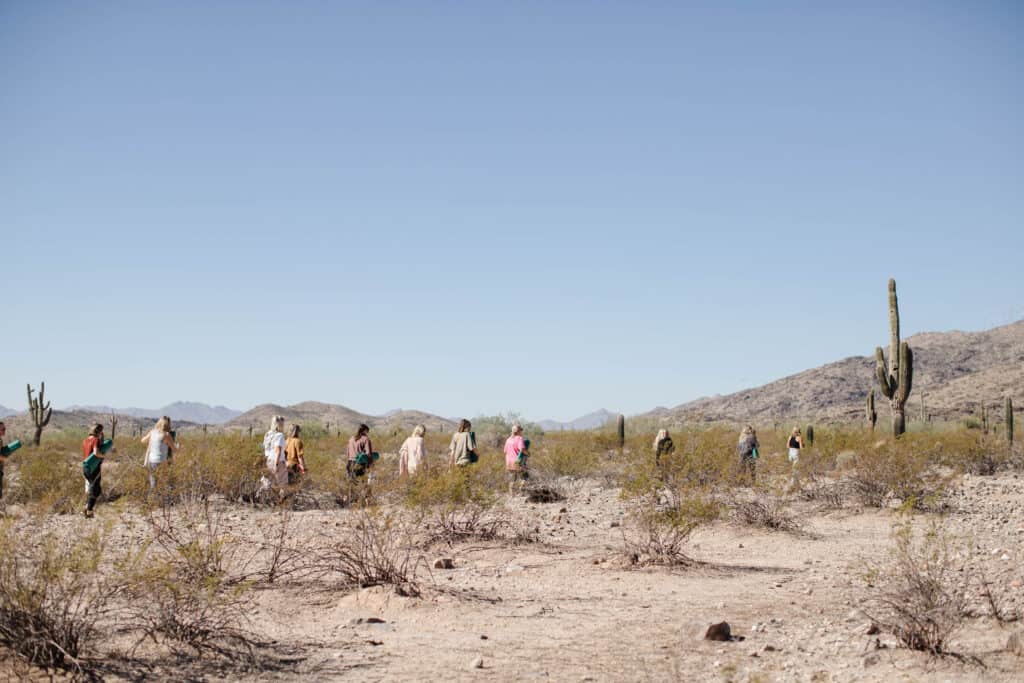 Women walking through desert to meditate with yoga mats