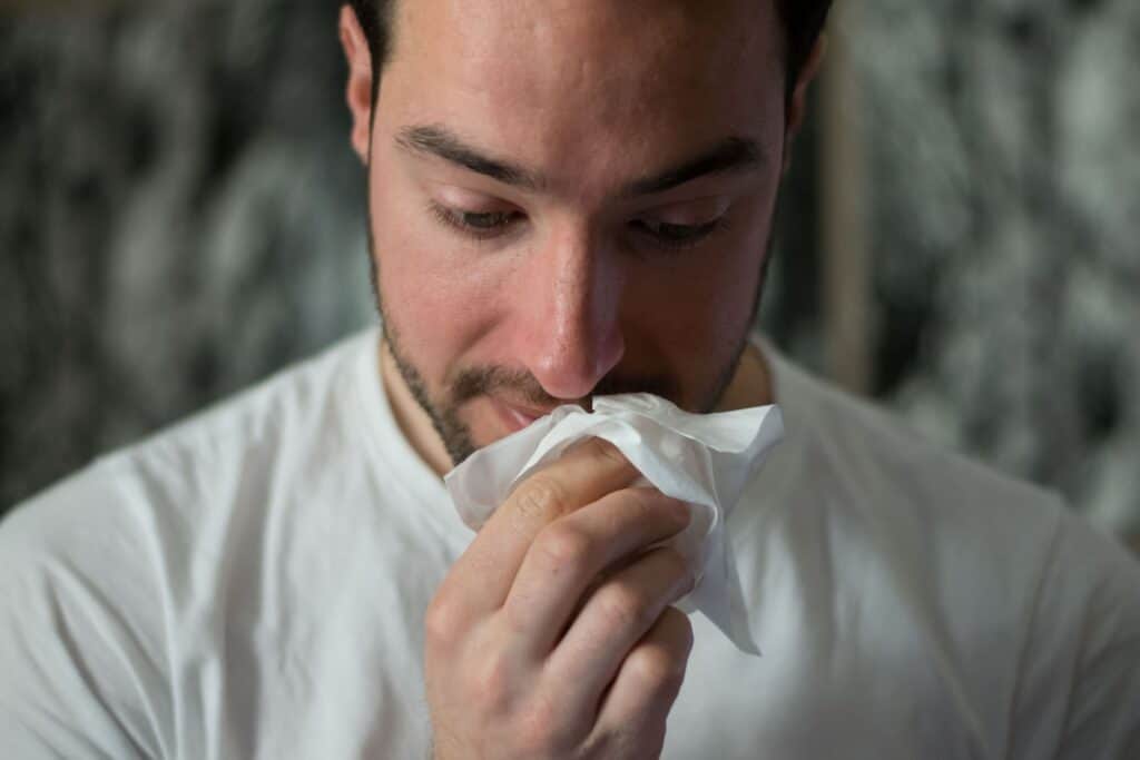 Man sneezing with tissue