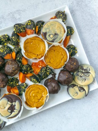 chocolate covered persimmons, chocolate pumpkin truffles and pumpkin cheesecakes with dark and white chocolate moons on white square serving platter